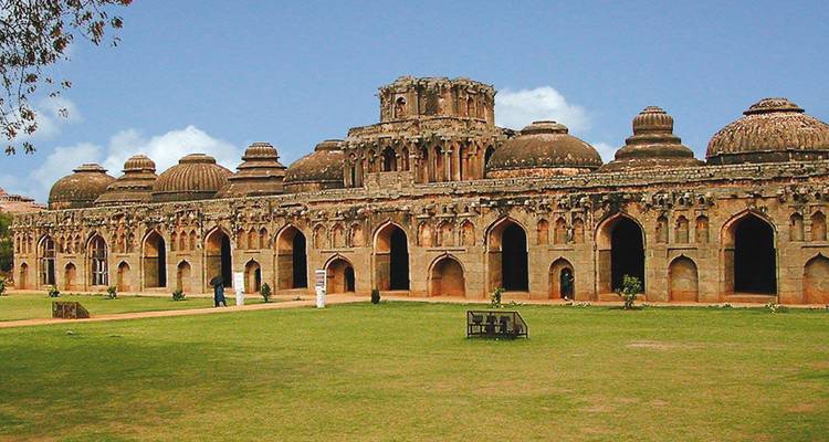 Structure de pierre ancienne avec des toits en forme de dôme dans une zone herbeuse.