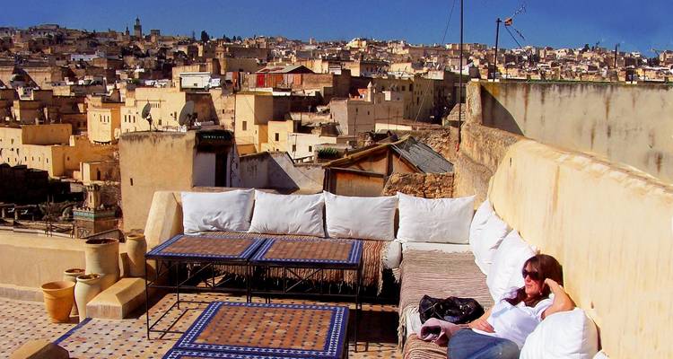 Person entspannt auf einer Dachterrasse mit Stadtblick.