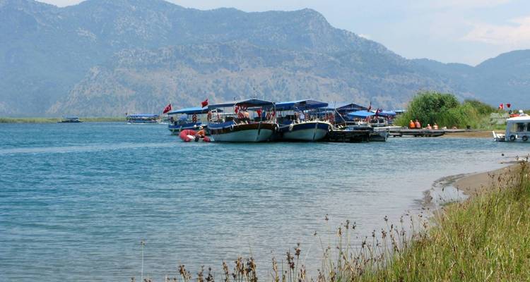 Tour boats on a river with hills behind.