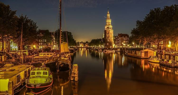Vista nocturna del canal e iglesia iluminada en Ámsterdam.