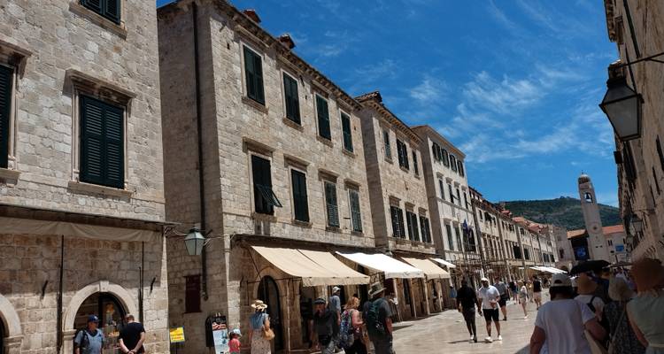 Una calle bulliciosa con edificios históricos de piedra y turistas caminando por los alrededores.