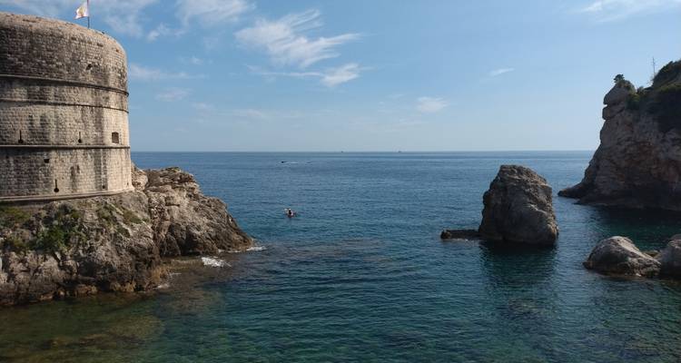 Una vista costera con murallas de fortaleza histórica y afloramientos rocosos en el mar.