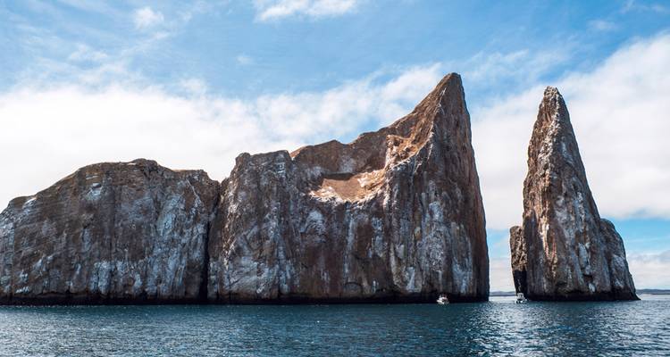 Towering rock formation Kicker Rock rising sharply from deep blue Pacific waters.