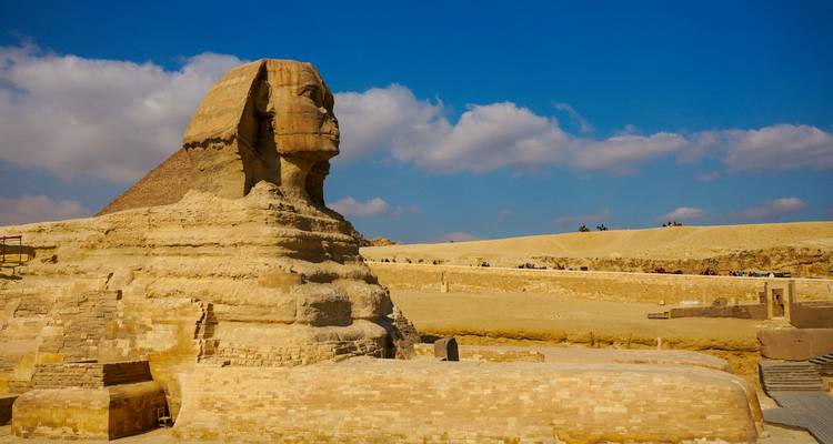 Zijprofiel van de Grote Sphinx met helderblauw lucht en verspreide wolken boven het Giza-plateau.