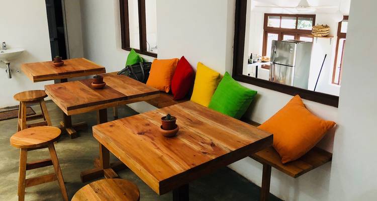 Intérieur de café simple avec des tables en bois, des tabourets et des coussins multicolores lumineux.