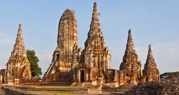 Los antiguos templos de ladrillo rojo de Wat Chaiwatthanaram se alzan dramáticamente contra un cielo azul.