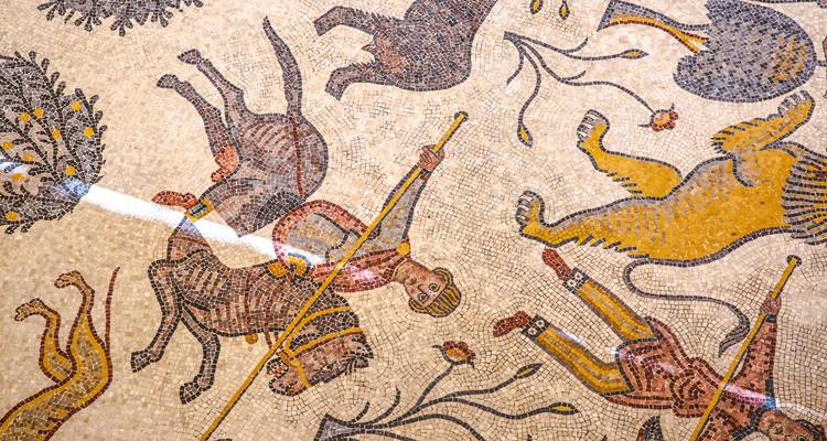 Detailed ancient mosaic depicting animals and hunters with vivid colours.
