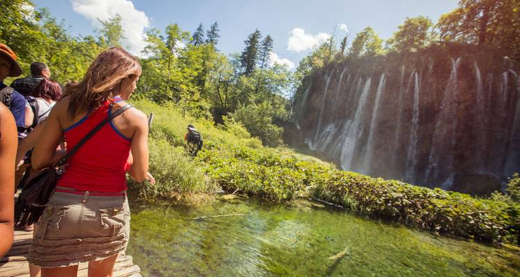 Bezoekers wandelen langs een houten pad naast de kristalhelder pools en watervalletjes van het Nationaal Park Plitvice Lakes.