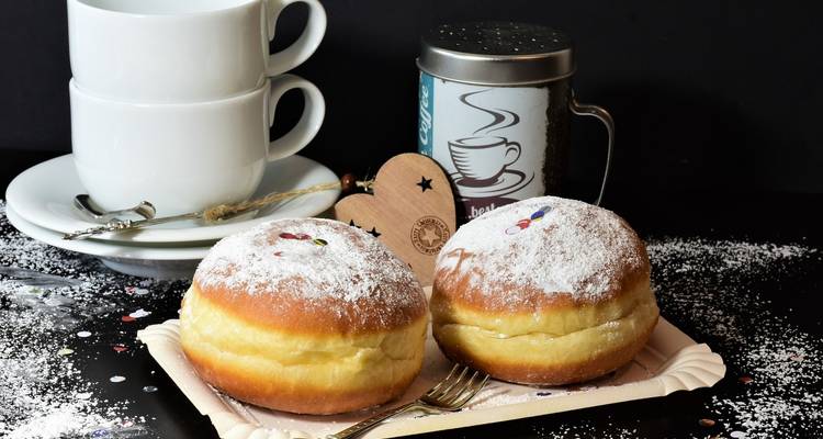 Deux pâtisseries avec du sucre en poudre, servies avec des tasses de café et des décorations.
