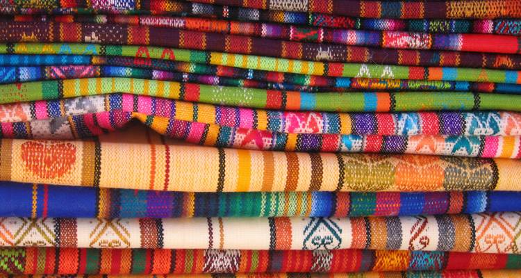 Pila de telas tejidas multicolores que muestran patrones andinos intrincados
