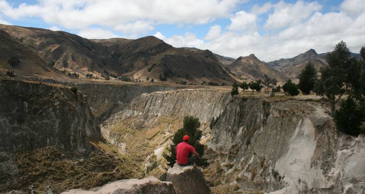 Person, die auf einem Felsen sitzt und einen Canyon überblickt.