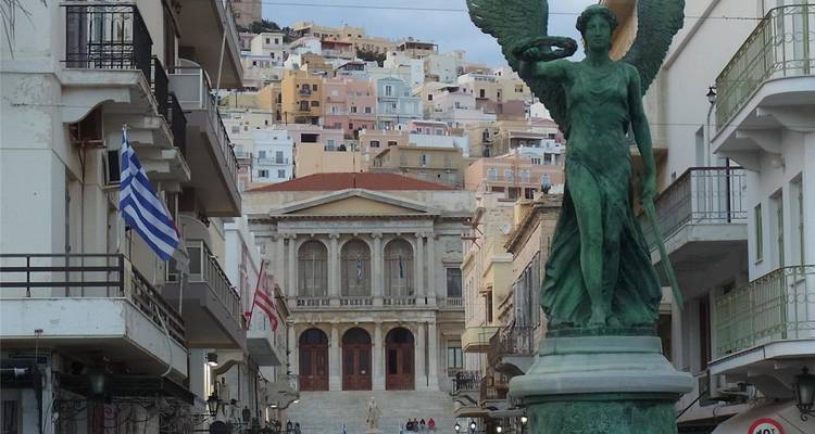Statue dans une ville avec des bâtiments colorés à flanc de colline.
