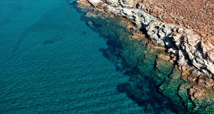 Vue aérienne d'une côte rocheuse avec une eau bleue claire.
