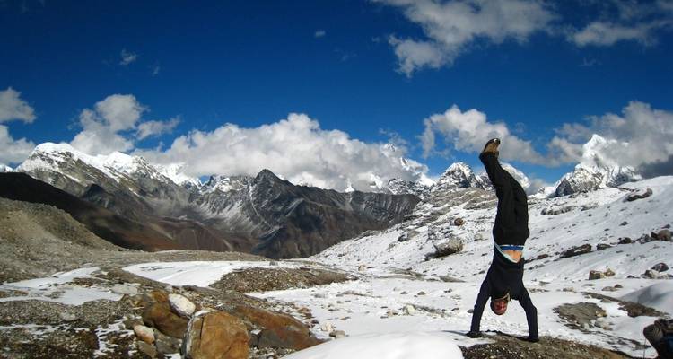 Eine Person macht einen Handstand in einer verschneiten Berglandschaft.