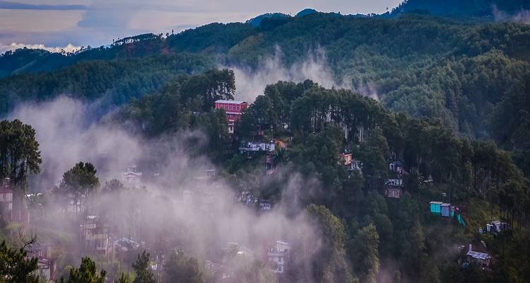 View over misty forested hills with houses.