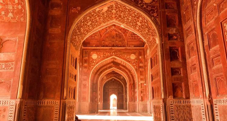 Rode zandstenen bogen en ingewikkelde houtsnijwerk binnen een historisch gebouw.