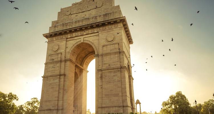 India Gate met vogels die rondvliegen in het avondlicht.