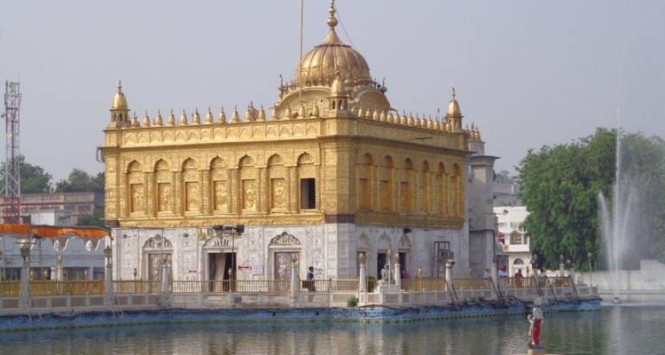 Gouden tempel weerspiegeld in het water met mensen eromheen.