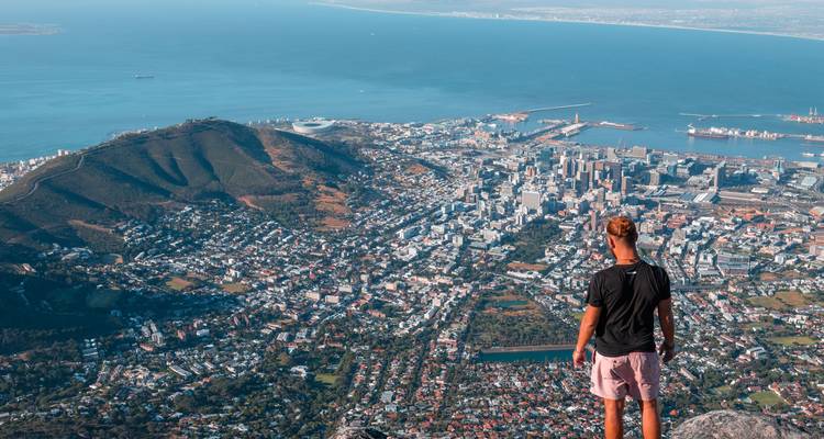 Person overlooking Cape Town from a mountain with a panoramic view.