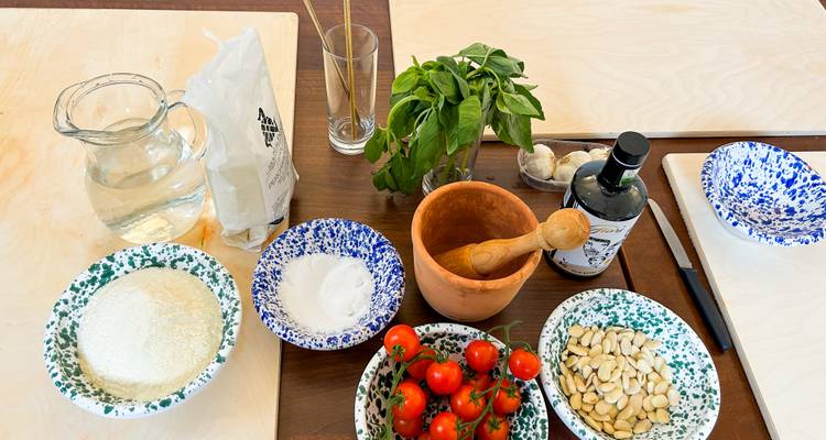 Présentation de table de tomates fraîches, de basilic, d'amandes et d'ingrédients culinaires prêts pour une recette.