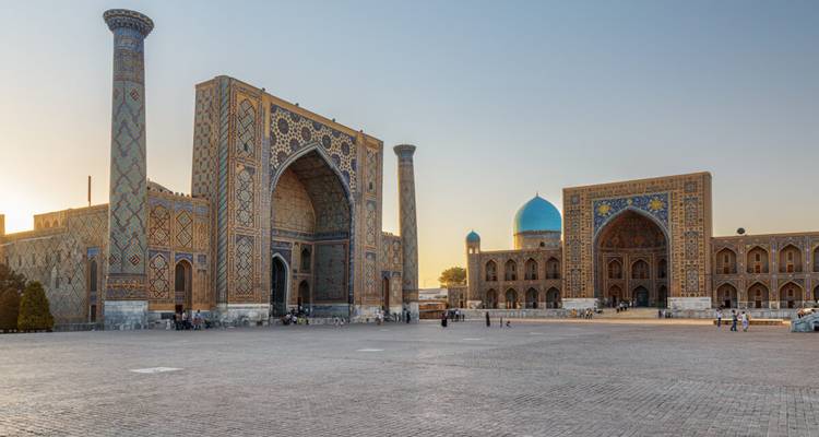 Die großartigen Medresen des Registan-Platzes leuchten sanft im frühen Morgenlicht vor einem klaren Himmel in Samarkand.