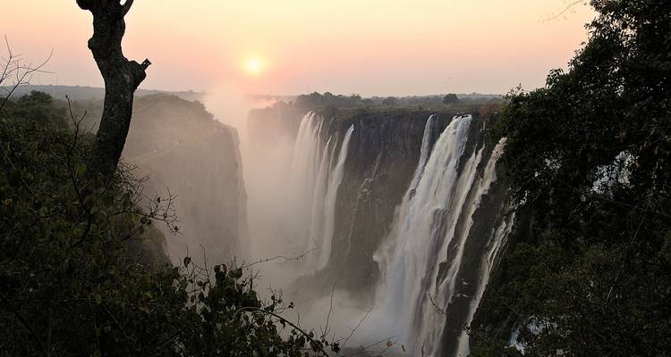 Cascada con entorno brumoso durante la puesta de sol.