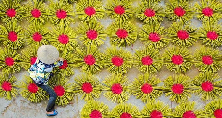 Personne manipulant des bâtons d'encens colorés au soleil.