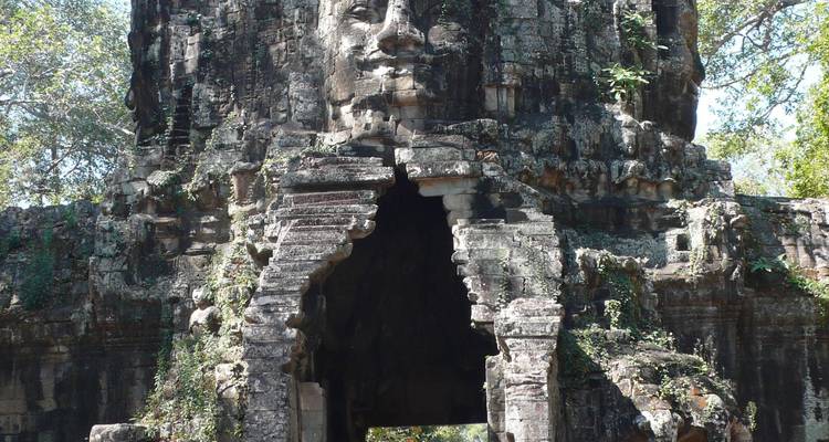 Entrée du temple sculptée d'un visage de pierre et de feuillages.