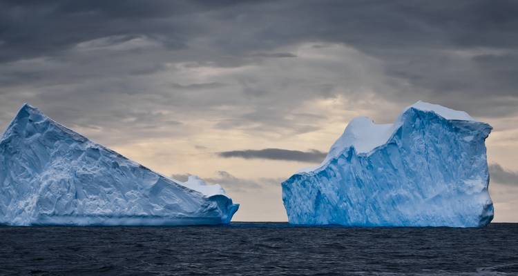 Deux grands icebergs sous un ciel nuageux