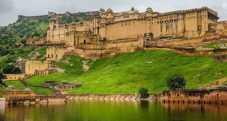 Amber Fort with green hills and lake.