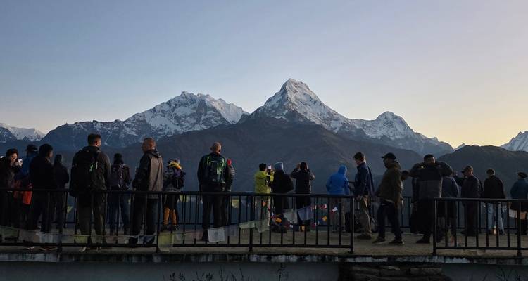 Des dizaines de trekkeurs se rassemblent sur une plateforme de point de vue à l'aube pour photographier les sommets de l'Himalaya.