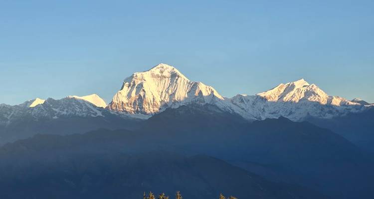 Large panorama himalayenne avec le Dhaulagiri s'élevant au-dessus des crêtes en couches dans la lumière cristalline du matin.