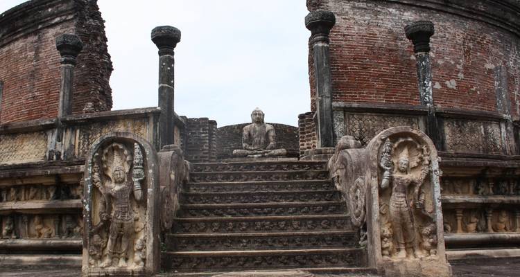 Structure de pierre ancienne avec des escaliers menant à une statue assise.