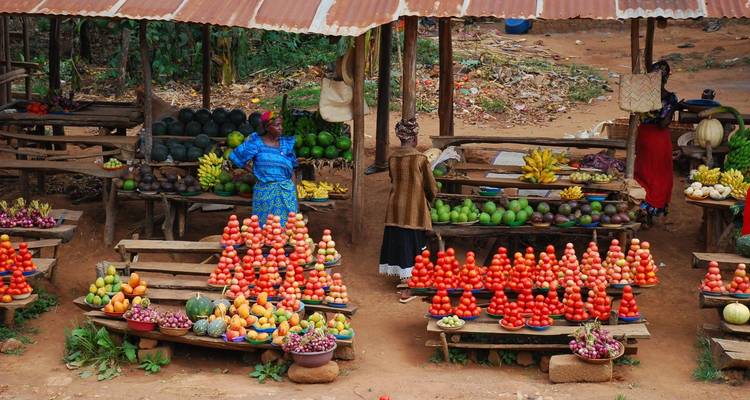 Mercado de frutas colorido con dos mujeres vendiendo productos.
