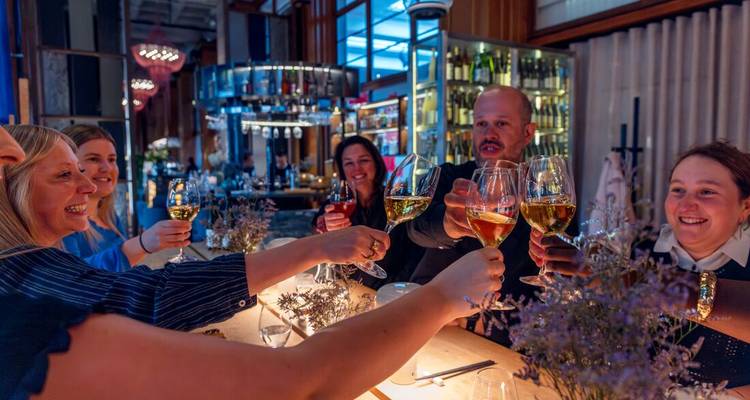 Gruppe von Menschen, die Getränke in einer Bar genießen und ihre Gläser erheben.