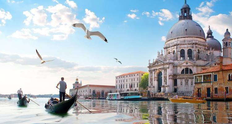 Gondels in een kanaal met een grote kerk aan de rechterkant.