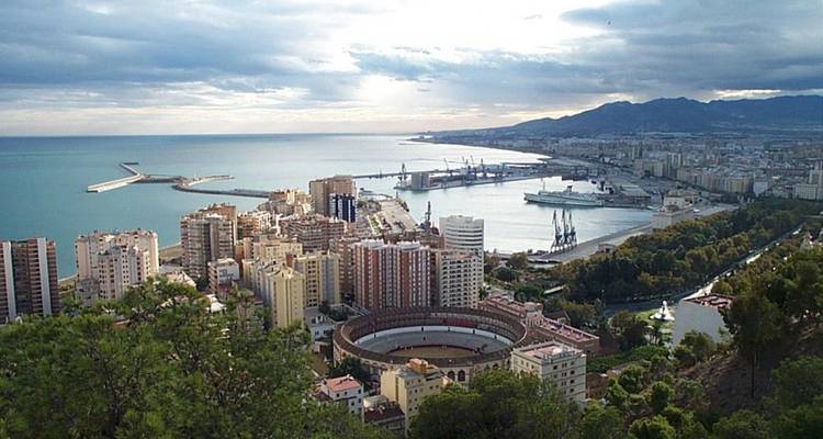 Vue aérienne d'une ville côtière avec une arène circulaire proéminente, peut-être Malaga.
