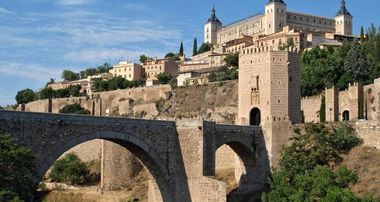 Une ville fortifiée sur une colline avec un grand pont de pierre à Tolède.