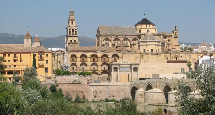 Un paysage urbain historique avec un pont et une cathédrale, mettant en valeur la ville de Cordoue.