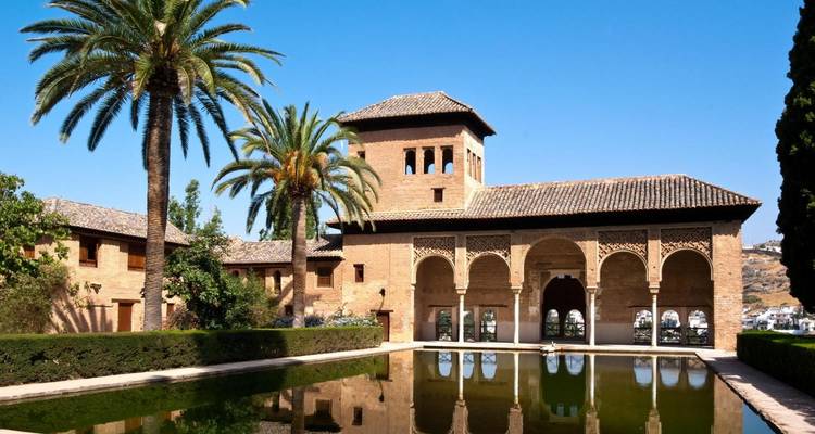 Une belle vue sur le palais de l'Alhambra et son bassin de réflexion entouré d'arbres luxuriants.