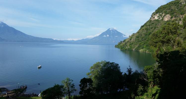Panoramic view of Lake Atitlán with distant volcanoes mirrored in still waters
