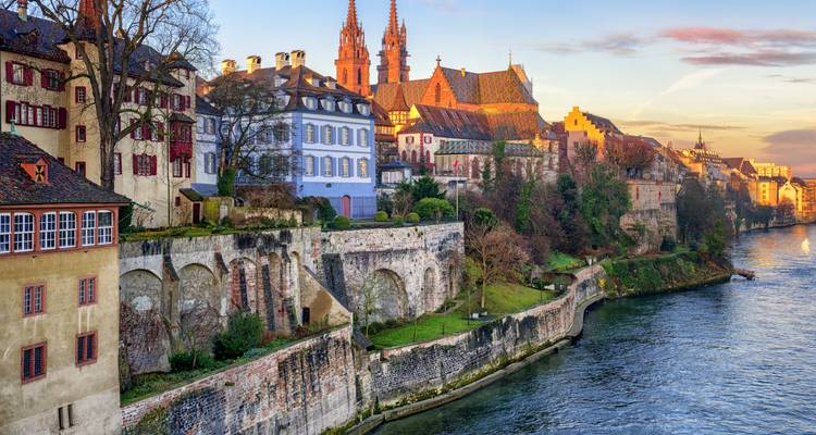 Edificios históricos junto a un río bajo un cielo vespertino vibrante.