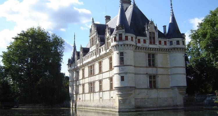 Historisches Schloss, umgeben von einem Wassergraben und üppigem Grün.