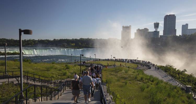 Des visiteurs aux chutes du Niagara avec un horizon urbain en arrière-plan.