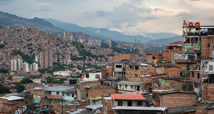 Vista panorámica de un paisaje urbano con edificios de apartamentos y montañas distantes.