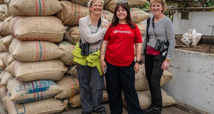 Turistas posando junto a sacos de mercancías en una zona de mercado.