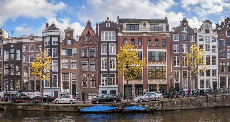 Traditionelle niederländische Grachthäuser in Amsterdam mit einer Gracht im Vordergrund.