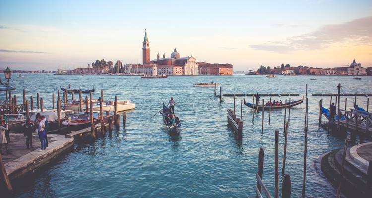 Góndolas y turistas en la laguna veneciana frente a la isla de San Giorgio Maggiore durante la suave luz del atardecer.