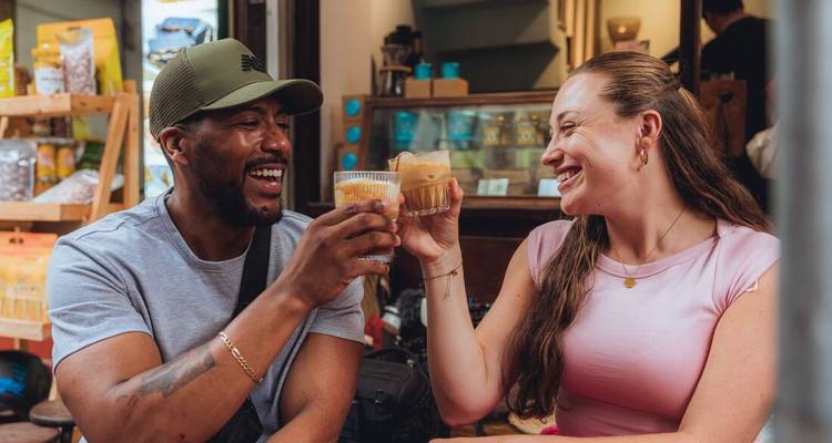 Pareja sonriente brinda con cafés helados vietnamitas en un acogedor café