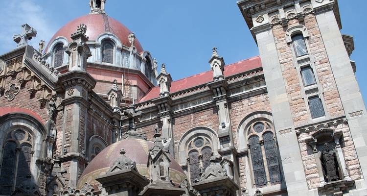 Komplexe Steinarchitektur mit Kuppeln und Türmen vor einem blauen Himmel.